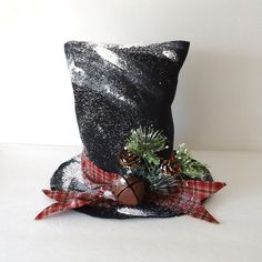 a black hat with red and white plaid ribbon, pine cones and holly on it