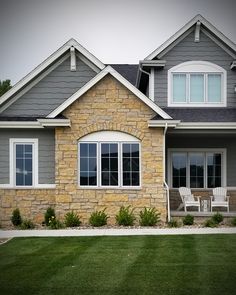 a house that has grass in front of it and two chairs on the lawn outside