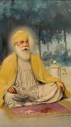 an old man sitting on the ground with headphones in his ears and wearing a yellow turban