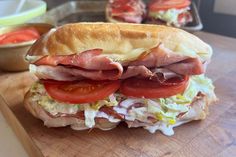 a ham and tomato sandwich on a cutting board