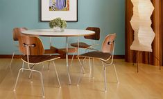 a dining room table with four chairs and a vase on the table in front of it