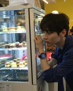 a young man looking at pastries in a display case