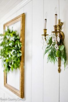 two wall sconces are hanging on the wall next to a wreath and candle holder