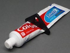 a tube of toothpaste sitting on top of a gray table next to a white bag