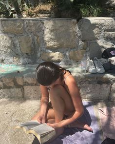 a woman sitting on the ground reading a book