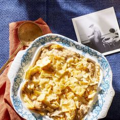 a blue and white plate topped with food next to an old photo on a table