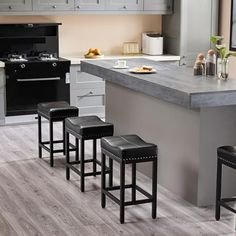 three stools sit in front of a kitchen island with two stoves and an oven