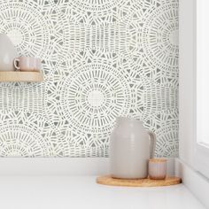 two vases sitting on top of a counter in front of a wallpapered background