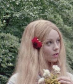 a woman with long blonde hair holding flowers