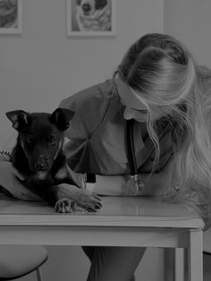 a black and white photo of a woman at a desk with a dog on her lap