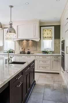 a large kitchen with white cabinets and marble counter tops, along with stainless steel appliances