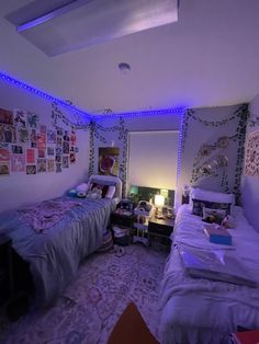 two beds in a room with purple lights on the wall and pictures hanging above them