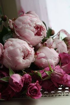 a bunch of pink flowers sitting on top of a white table next to a mirror