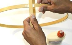 two hands are working on an object with glue and wood strips in front of them