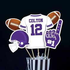 a cake topper with footballs and helmets on it, sitting in a cup