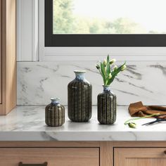 two vases with flowers are sitting on the counter