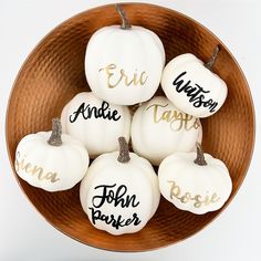 white pumpkins with black writing on them in a bowl