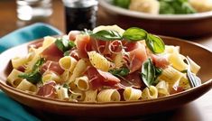 a plate of pasta with ham and basil