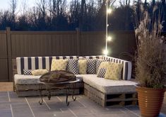 an outdoor seating area with couches and lights on the side of the fenced in area