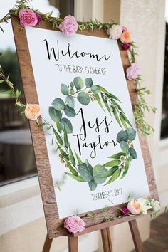 a sign with flowers and greenery on it