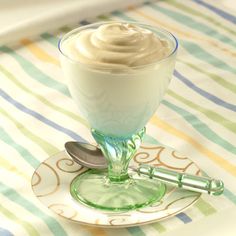 a glass filled with whipped cream sitting on top of a table next to a plate