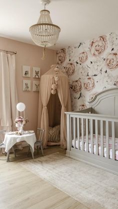 a baby's room is decorated in pink and white flowers, with a crib next to the bed