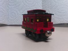 a red toy train car sitting on top of a white table next to a wall