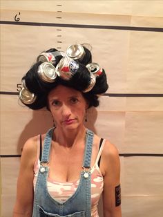 a woman in overalls with cans on her head and hair rollers on her head