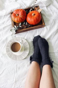 a person laying on a bed with their feet up next to a cup of coffee