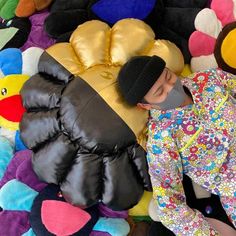 a person laying on top of a pile of stuffed animals and beanie hats with their eyes closed