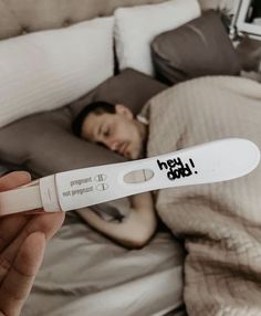 a person laying in bed with an electronic thermometer