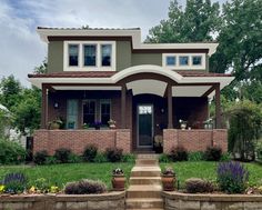 a house that is in the middle of some grass and flowers on the front lawn