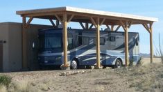 an rv parked under a wooden structure in the desert