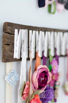 flowers are hanging on the wall next to clothes pins