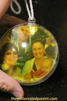 a hand holding a glass ornament with two people in the center and one person's face on it