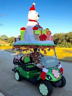 a person driving a golf cart with a large christmas bear on it's back