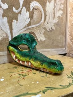 Crocodile Mask Traditional and original Venetian mask made of papier-mâché, handmade and decorated with acrylic paints, oil colors and wax. All our masks are handmade in our shops located in Venice. Our decorators use traditional Venetian techniques such as stucco, acrylics, gold and silver leaf, macramé, passemenerie, pearls and crequelè to offer a wide range of masks. This mask is unique, which is why the decoration and color shades may differ from the one in the photo. We ship worldwide with Crocodile Mask, Costume Masks, Venetian Mask, Costume Mask, Mask Making, Acrylic Paints, Silver Leaf, Color Shades, Costume Accessories