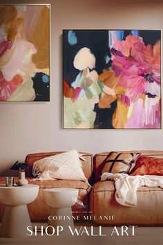 two paintings hang on the wall above a couch