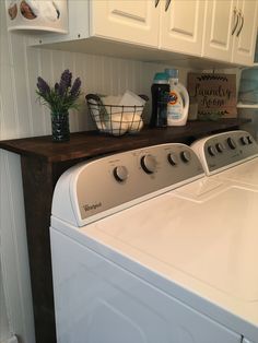 a washer and dryer sitting next to each other in a room with white cabinets