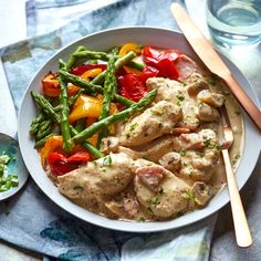 a white bowl filled with chicken and veggies next to a glass of water