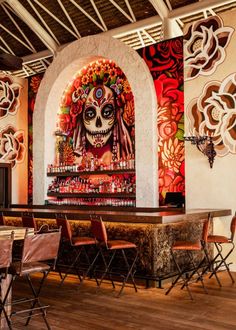 a mexican themed bar is decorated with sugar skulls and colorful flowers on the back wall