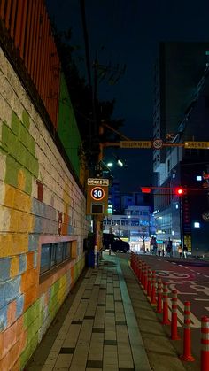 an empty city street at night with traffic lights and signs on the side of the road