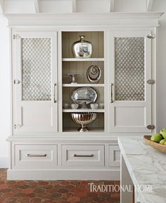 a white china cabinet with glass doors and drawers on the front, in a kitchen