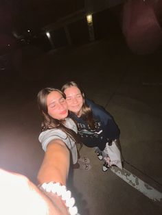 two young women taking a selfie in the dark with their arms around each other