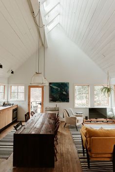 a dining room table with chairs and a couch in front of the window on the far wall