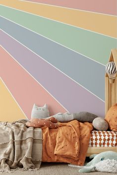 a bed with pillows and blankets in front of a colorful wall