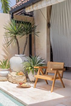 a wooden chair sitting on top of a patio next to a potted palm tree