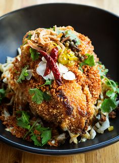 a black bowl filled with food on top of a wooden table