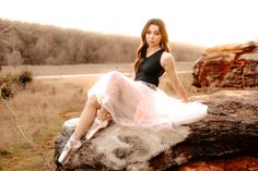 a woman sitting on top of a large rock