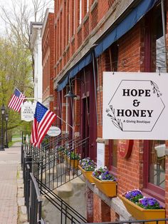 a sign that says hope and honey on the side of a building with flowers in front of it